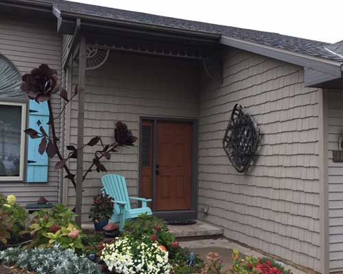 A house with a porch and a blue chair in front of it.