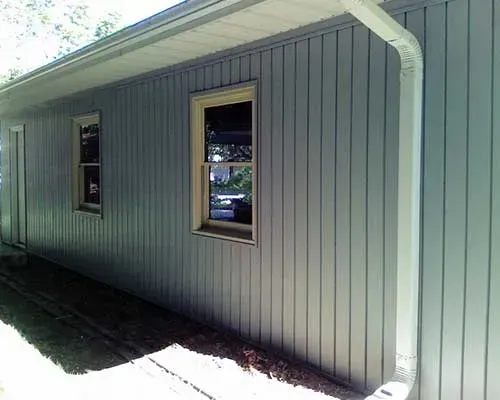 A gray house with two windows and a white gutter.