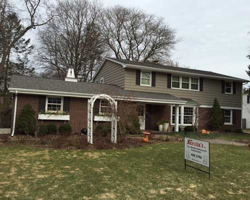 A large brick house with a sign in front of it.