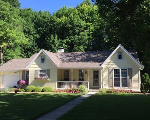 A white house with a porch and trees in the background