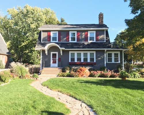 A house with red shutters and a walkway leading to it