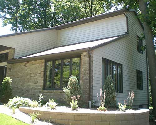 A house with a lot of windows and a brick wall in front of it