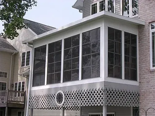 There is a screened in porch on the side of a house.