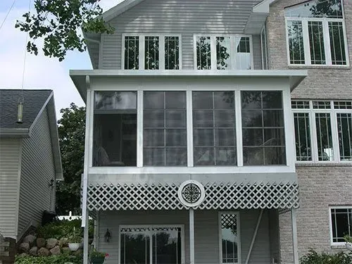 A house with a screened in porch and lots of windows