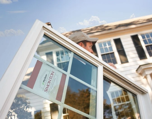 A man is installing a window with a sign that says simonton