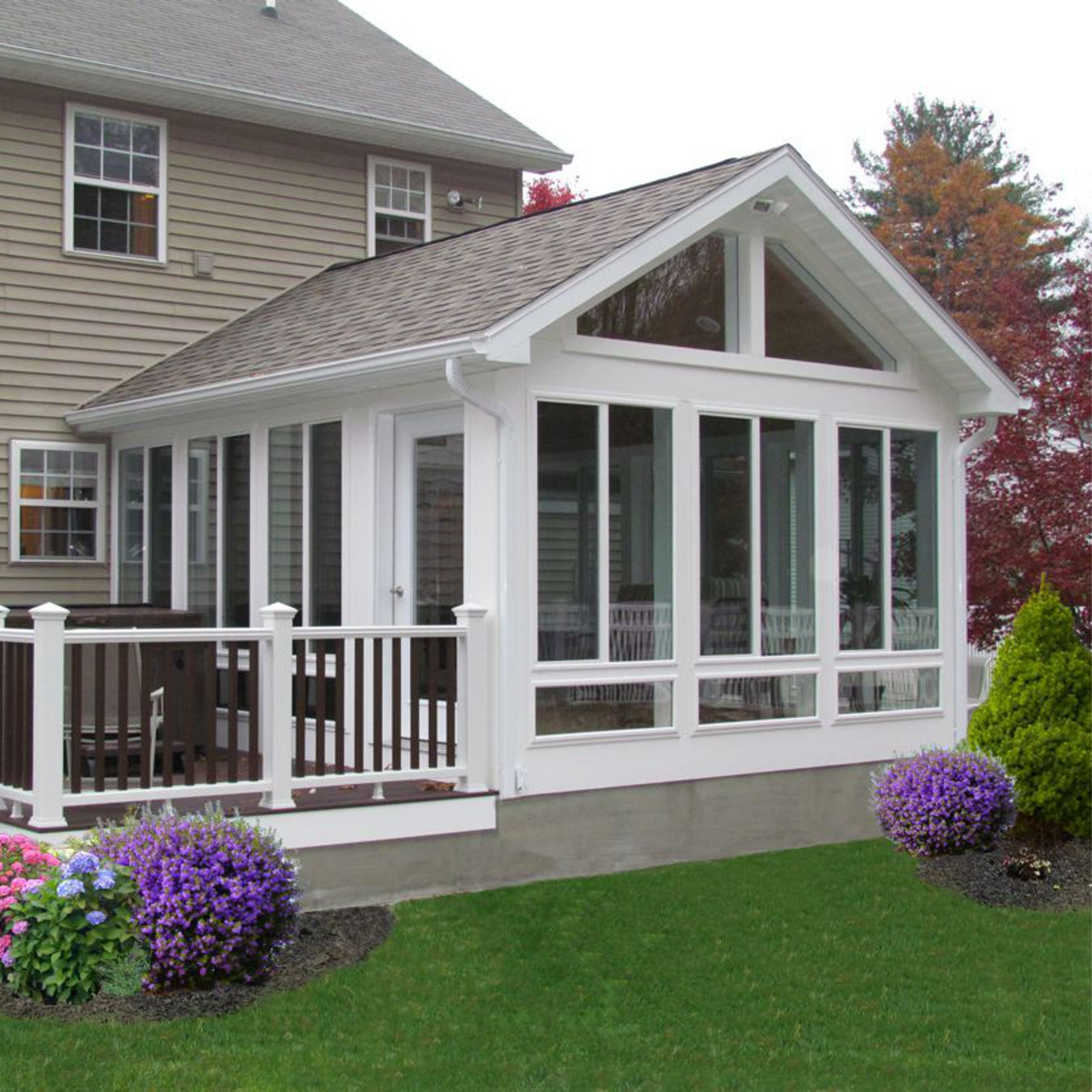 A house with a screened in porch and purple flowers