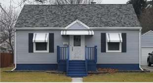 A small house with blue stairs and black shutters
