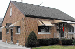 A brick house with awnings on the windows