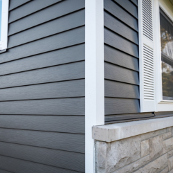 A corner of a house with gray siding and white trim