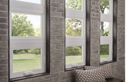A living room with three windows and a brick wall.