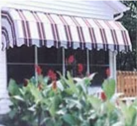 A white house with a red and white striped awning on the porch.