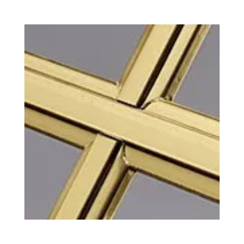 A close up of a brass cross on a gray background.