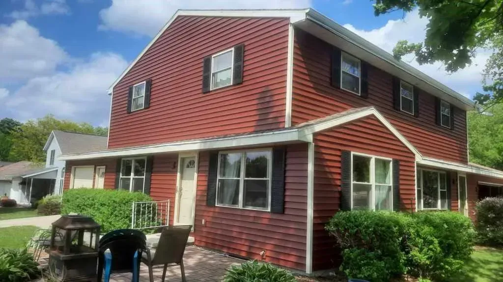 A large red house with black shutters and a patio in front of it.