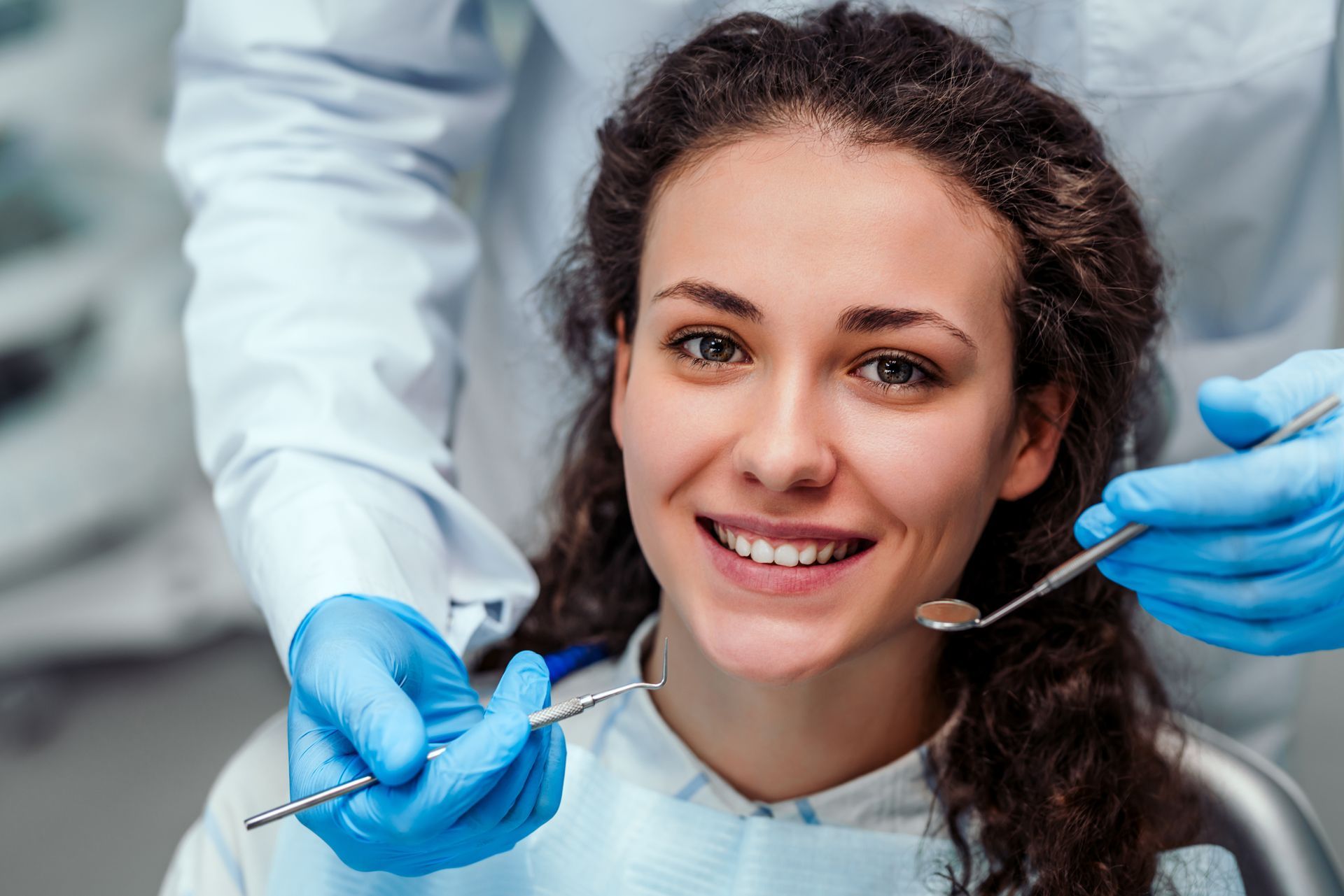 Smiling dental patient with open mouth as the dentist uses tools during a checkup.