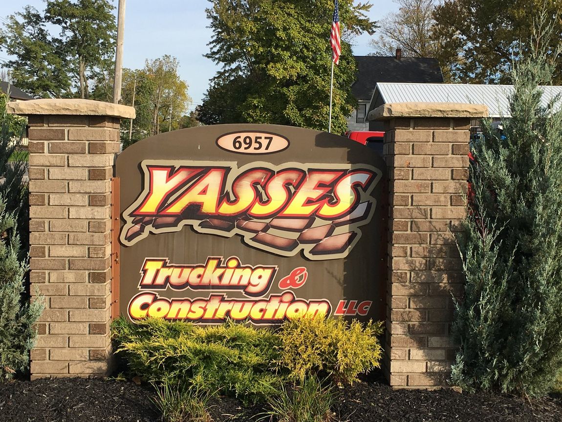 Yasses Trucking & Construction logo on a brick street sign
