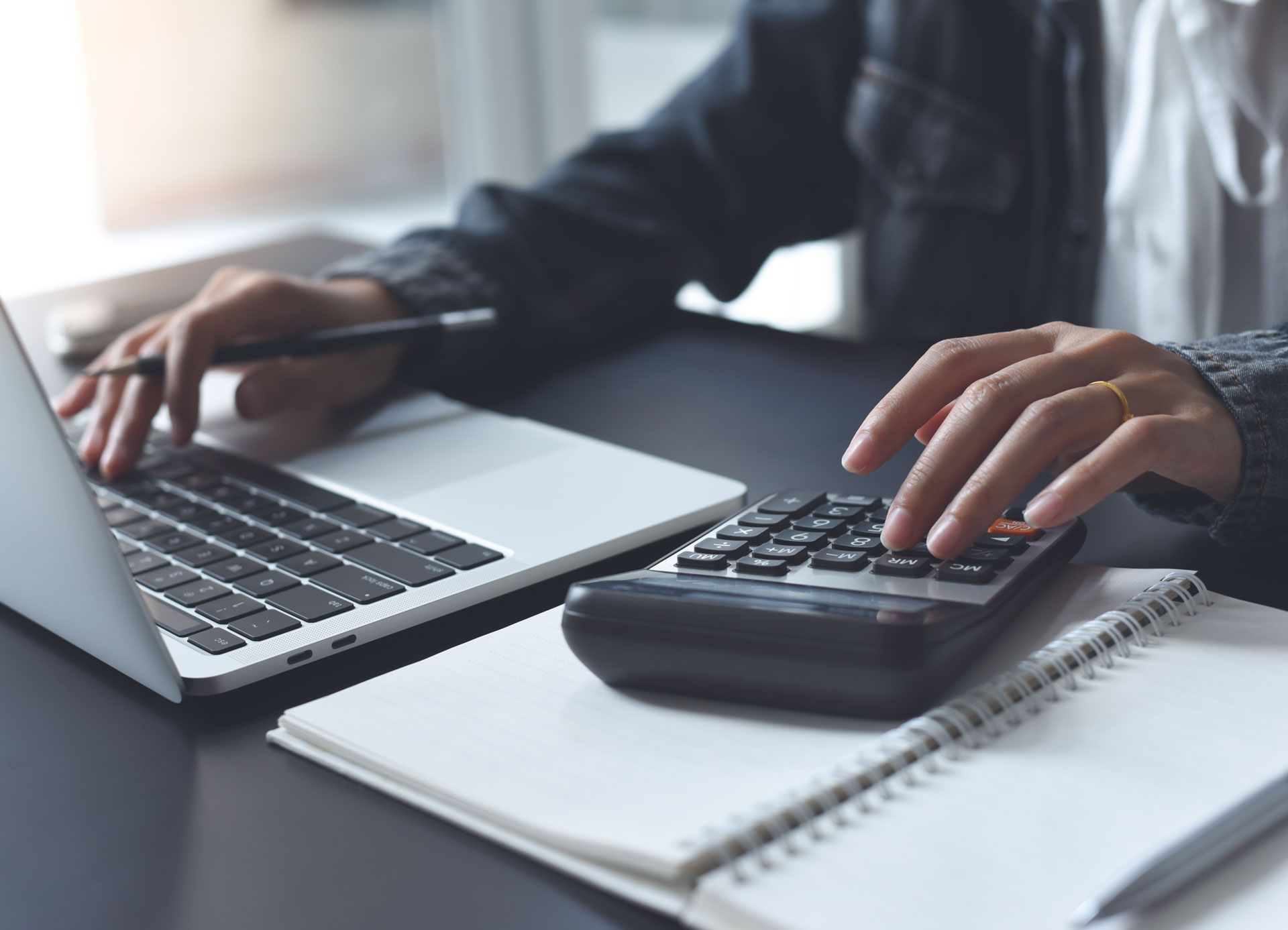 A person is using a laptop and a calculator at the same time.