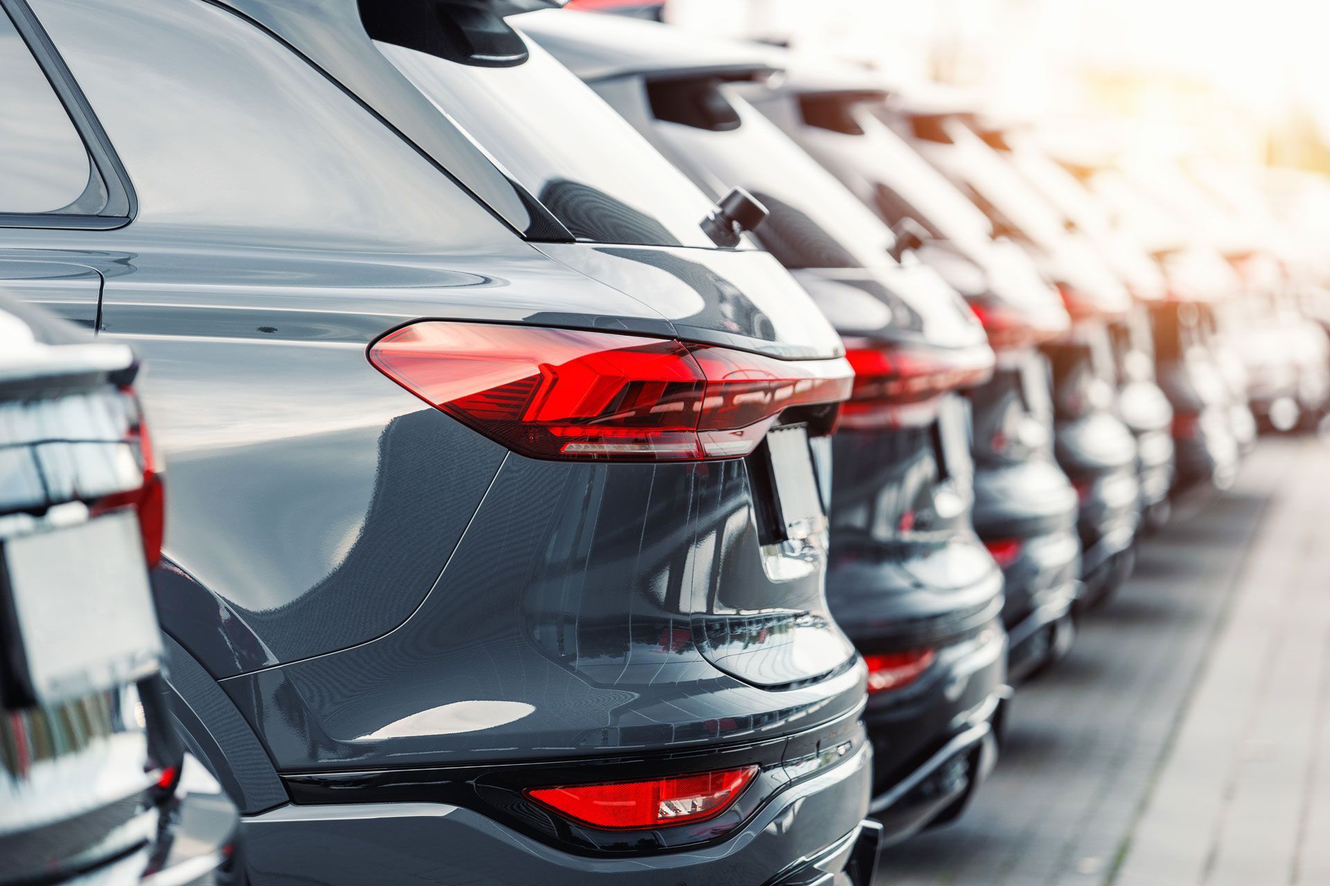 A row of cars are parked in a row at a car dealership.