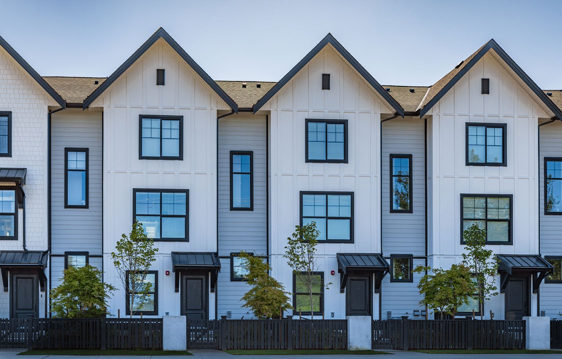 A row of white houses with black trim are lined up in a row.