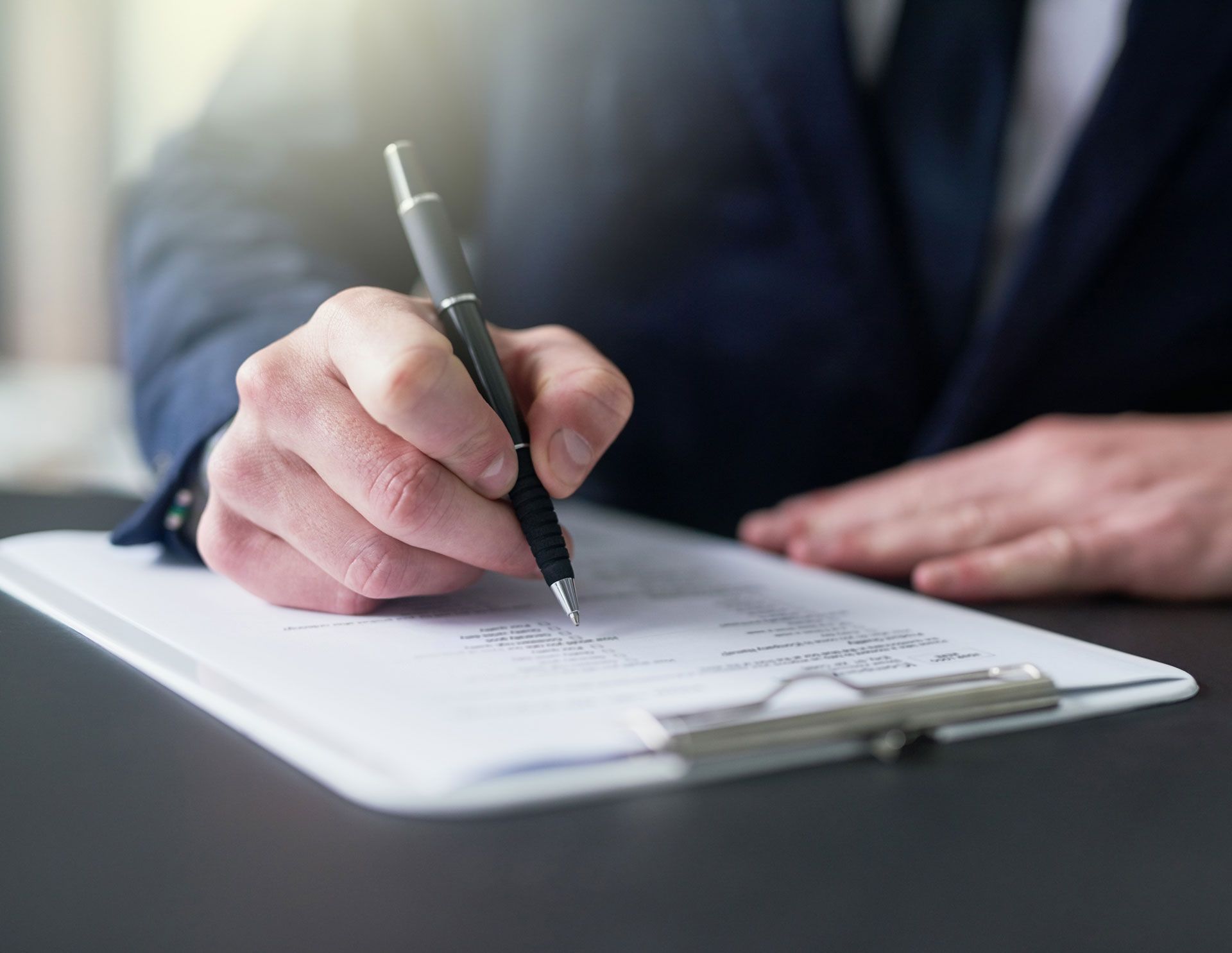 A man is writing on a clipboard with a pen.