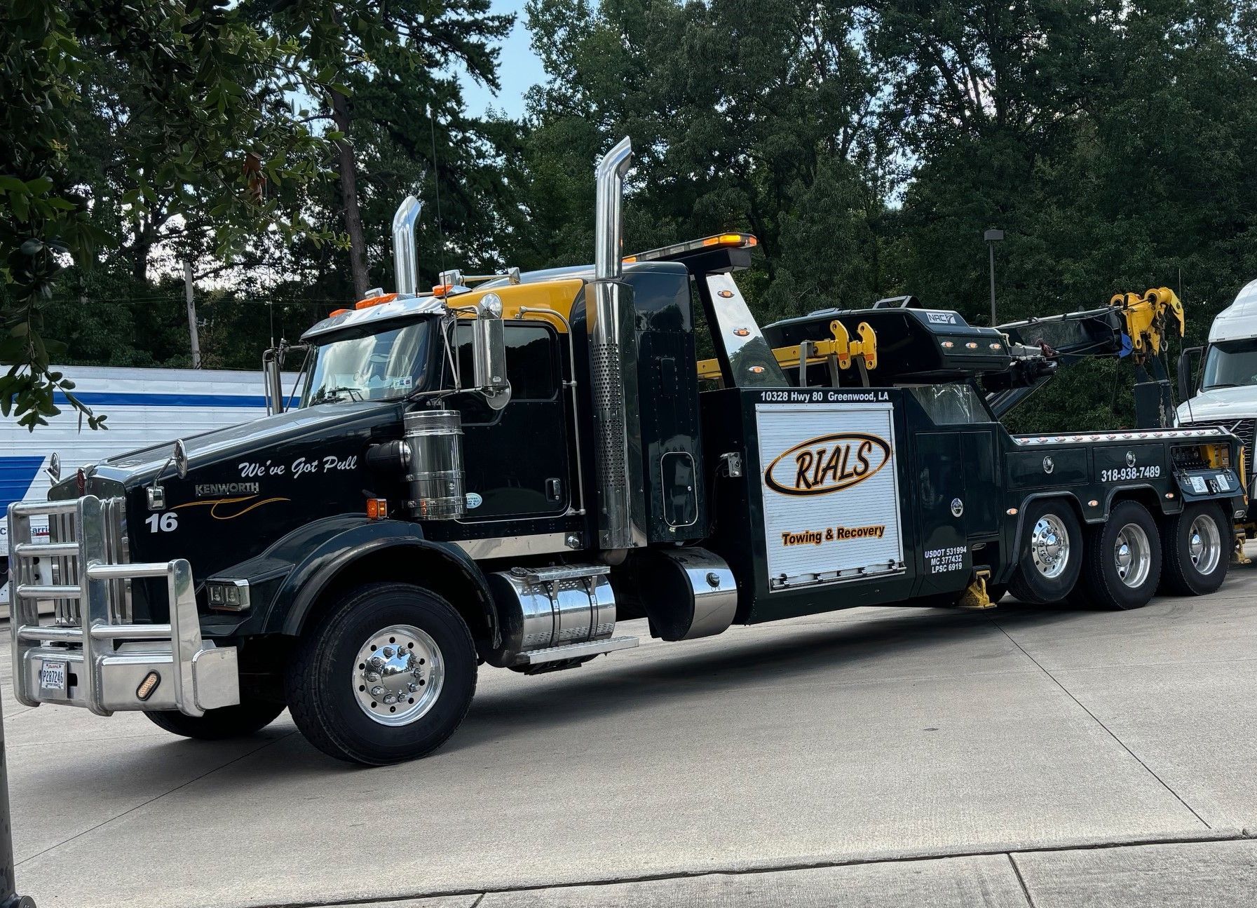 A large tow truck is parked on the side of the road.