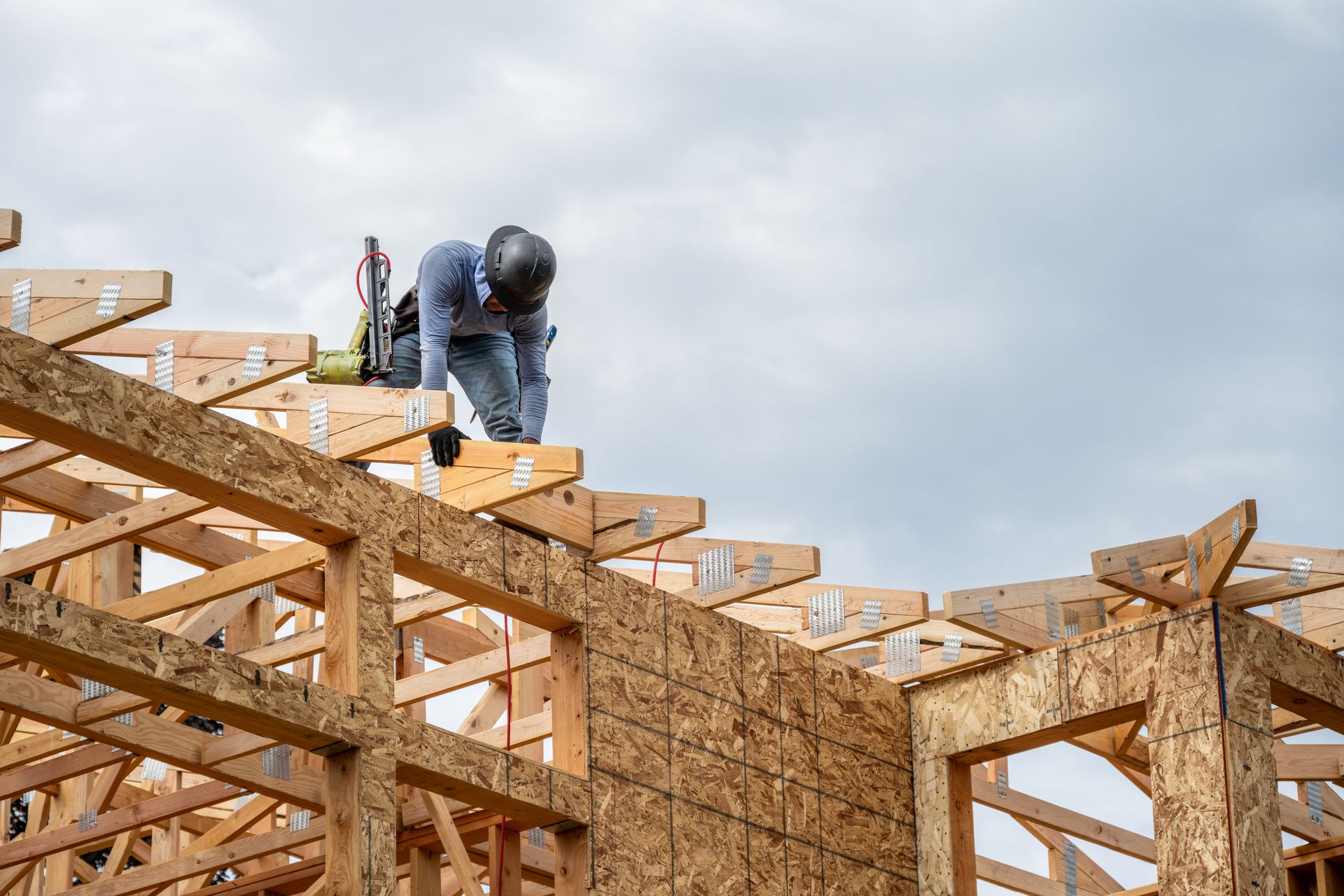 Low-angle view of male carpenters working on the rooftop of a construction frame.