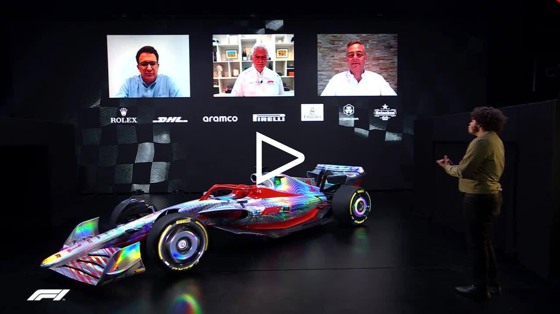 a man is standing next to a colorful race car in front of a large screen .