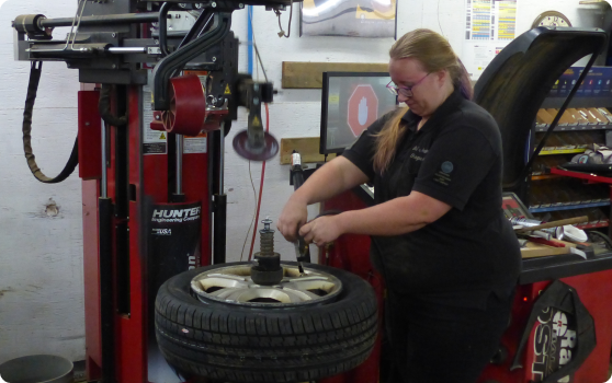 A woman is working on a tire | BJ’s Automotive Diagnostic Center