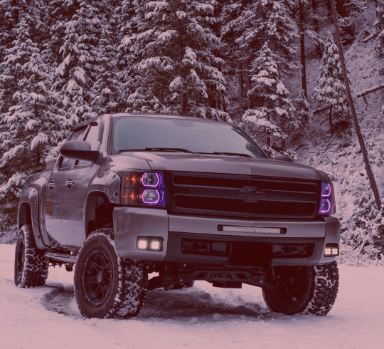 Truck with purple headlights is parked in the snow | BJ’s Automotive Diagnostic Center
