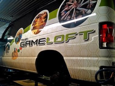 A white van with the word Gameloft on the side is sitting on a lift | BJ’s Automotive Diagnostic Center