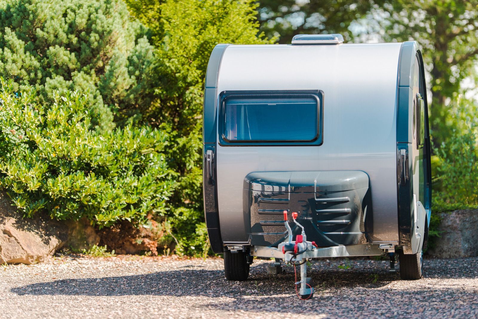 A small camper trailer is parked in a gravel lot.