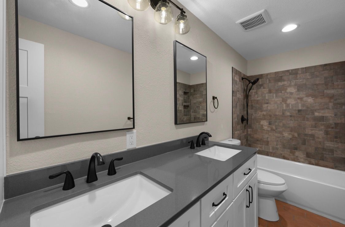Modern bathroom with double vanity, large mirrors, and a tiled shower-tub area