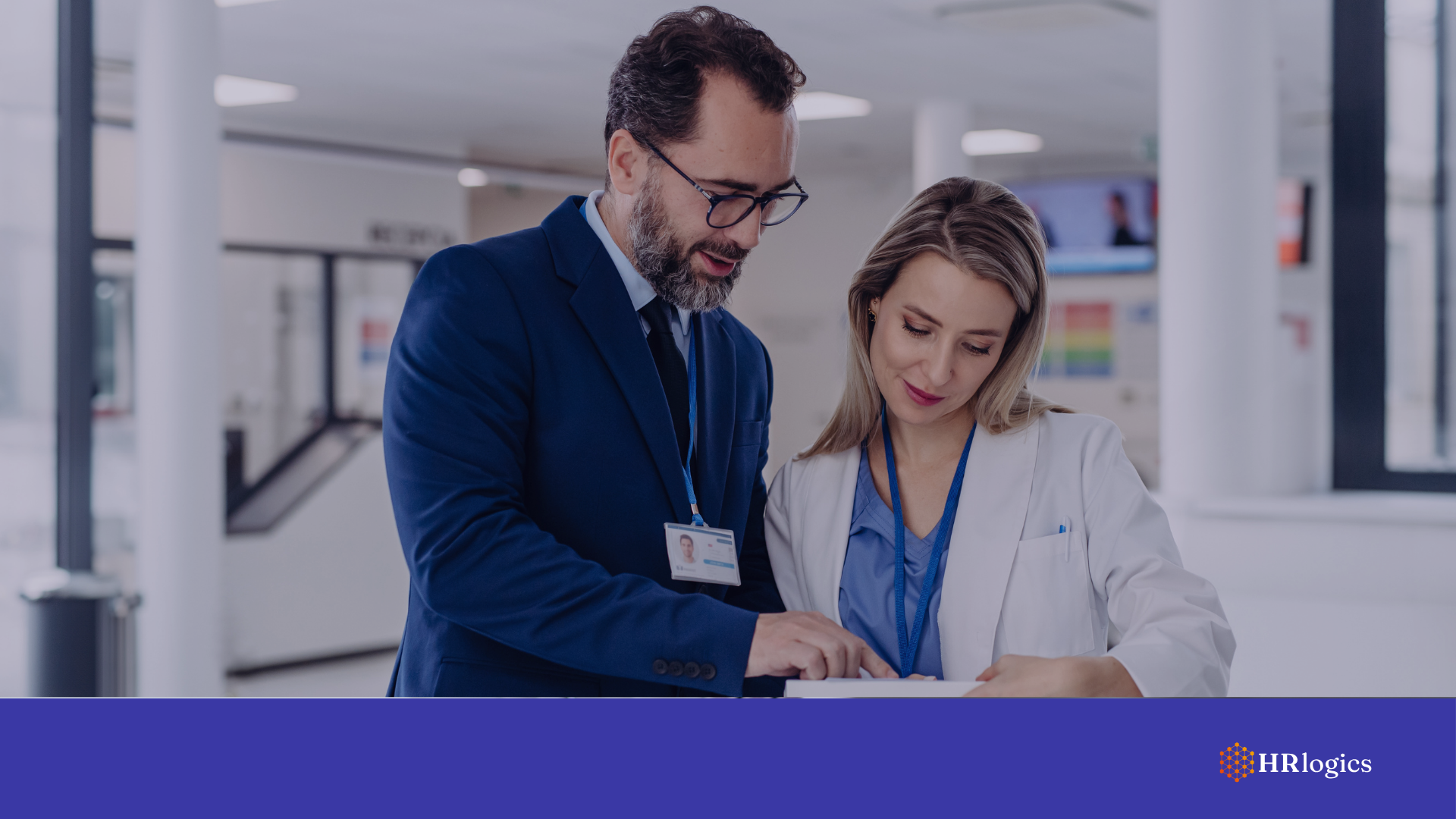 Male hospital executive and female healthcare worker reviewing documents in a medical facility.