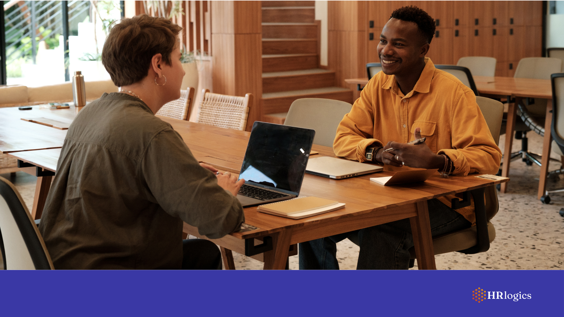 A recruiter interviewing a candidate in a modern office, with digital documents on screen.