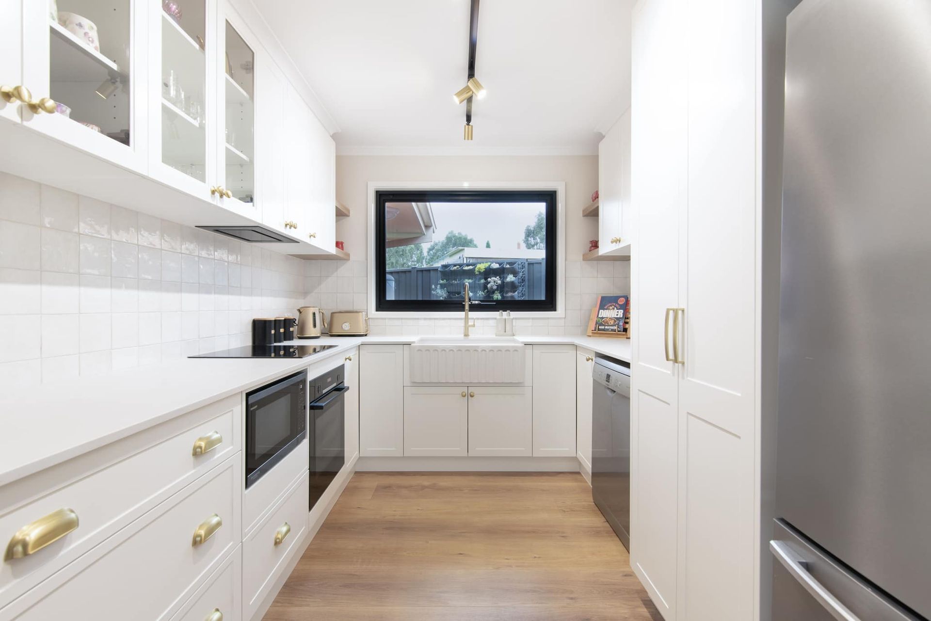 A kitchen with white cabinets , stainless steel appliances , and a large window.