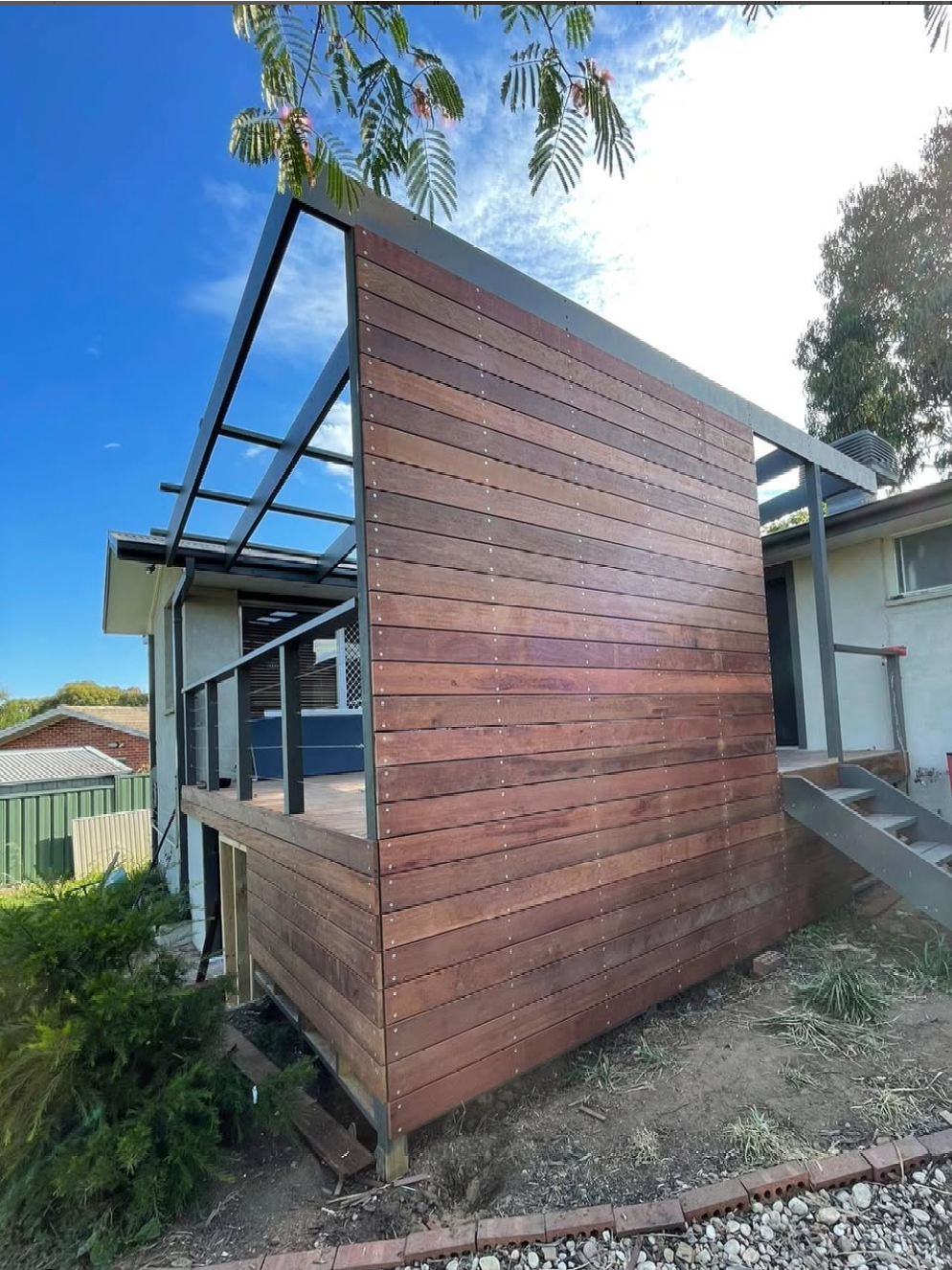 A small wooden house with a balcony and stairs.