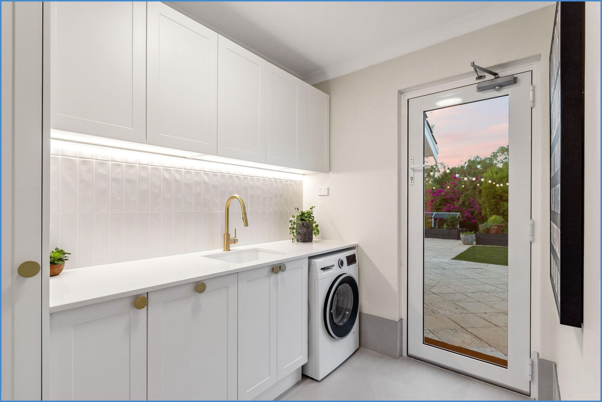A laundry room with a washing machine and a sink