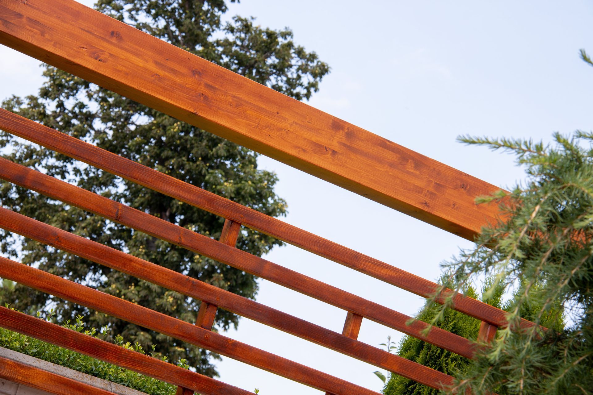A close up of a wooden railing with trees in the background.