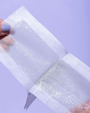 A person is holding a piece of wax paper with glitter on it.