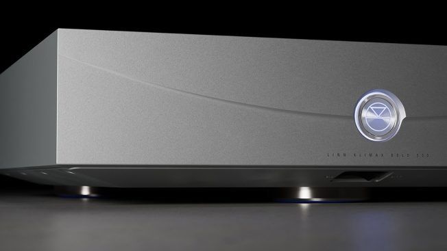 Silver audio component with curved face and glowing logo on a dark background.