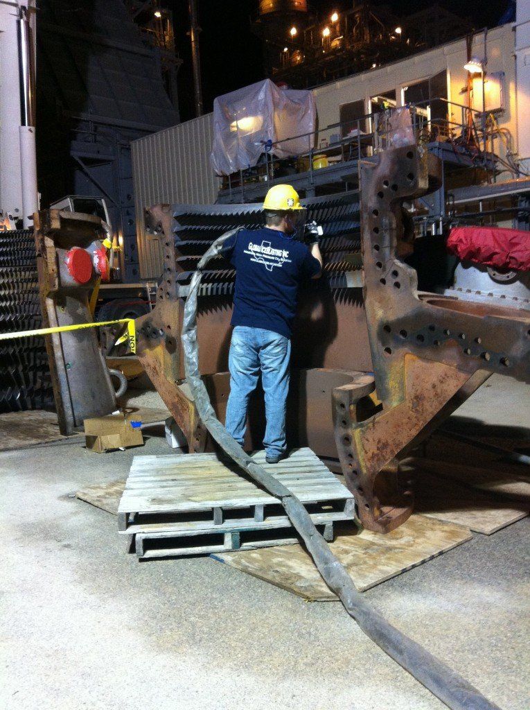 A man wearing a hard hat is working on a large piece of metal