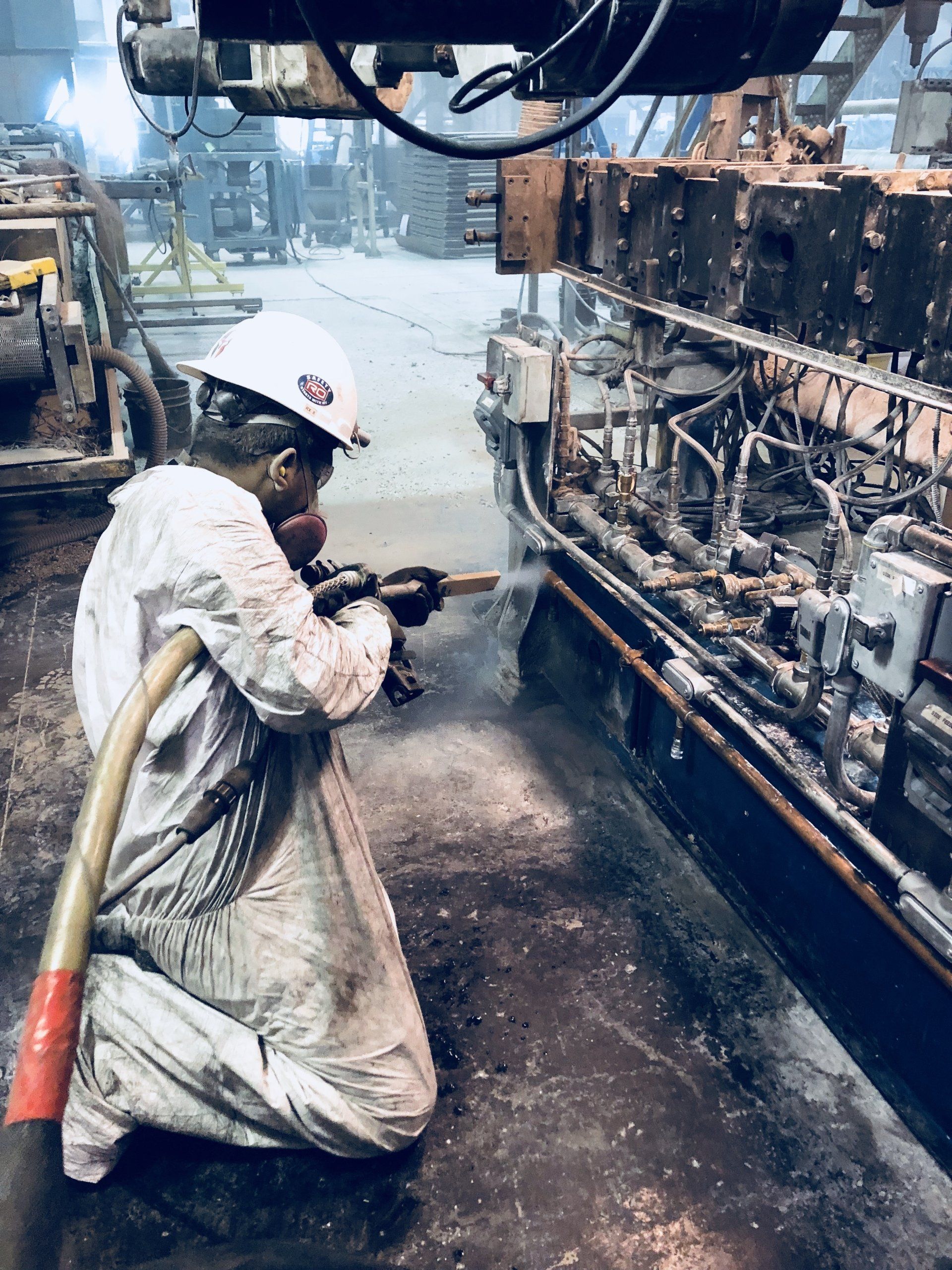 A man is kneeling down in front of a machine in a factory.