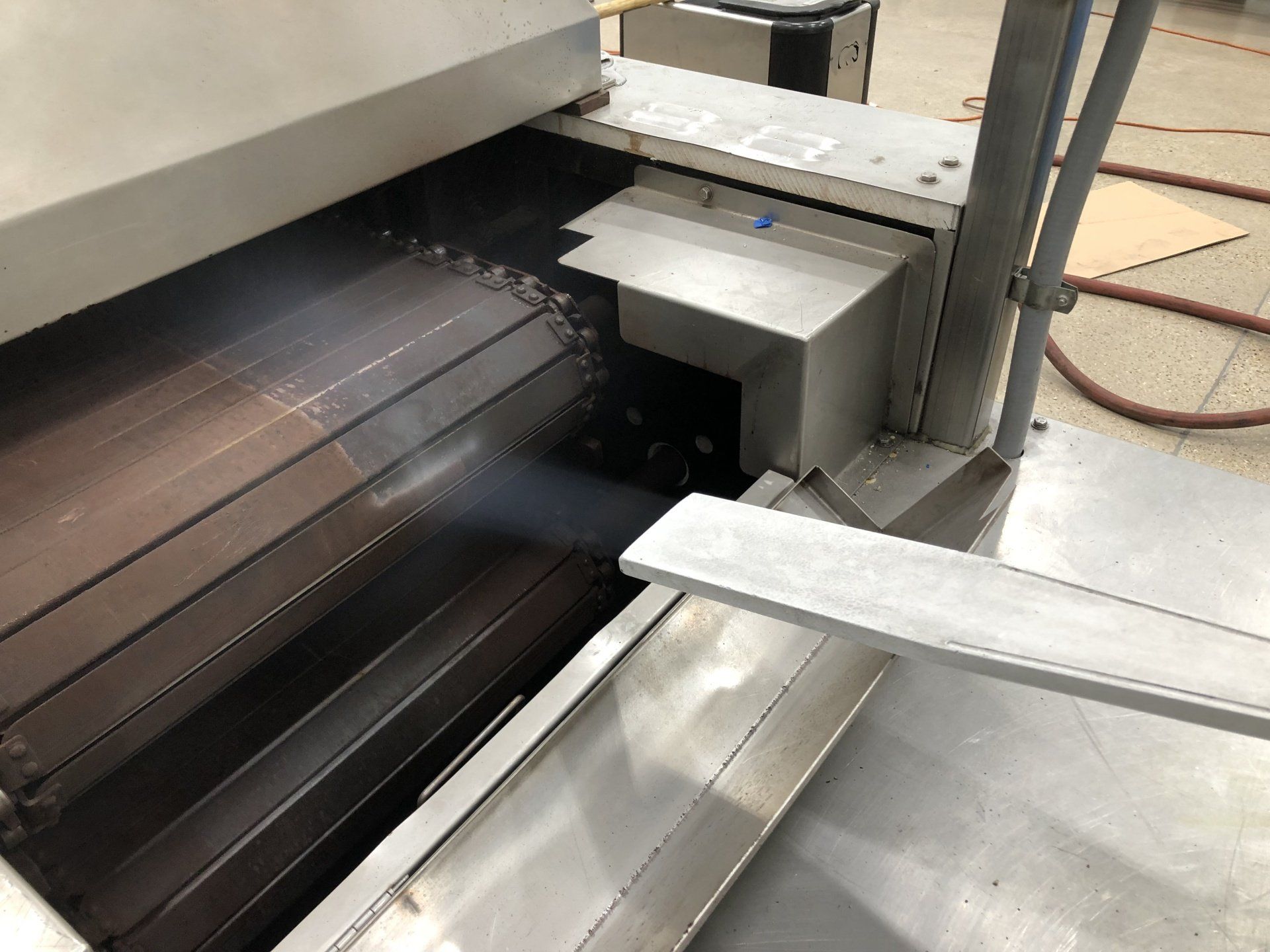 A stainless steel machine is sitting on the floor in a room.