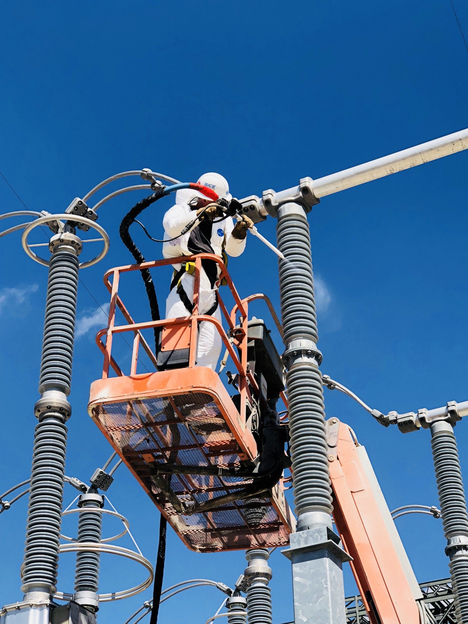 A man is standing on a crane working on a power line