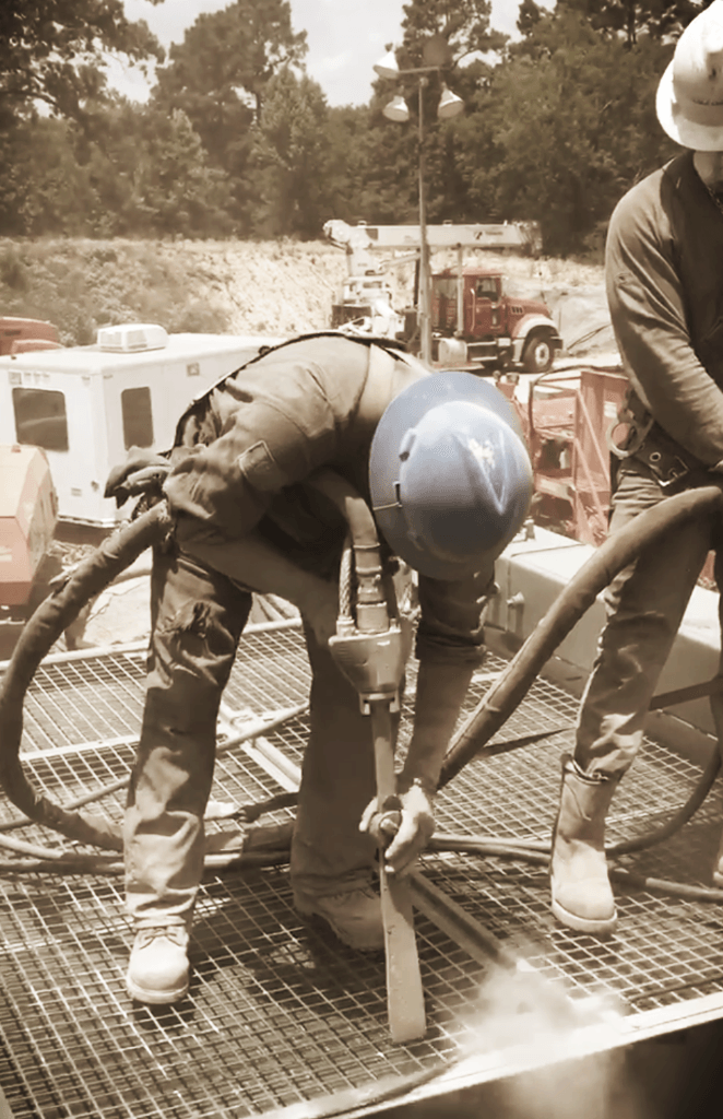 A man wearing a blue hard hat is using a hose