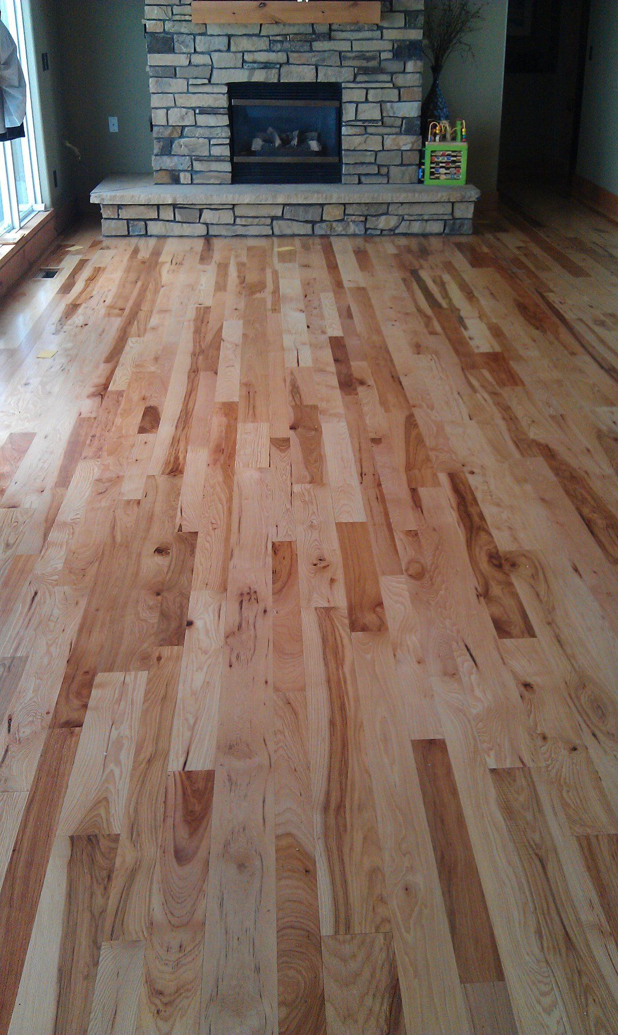 Woman in straw hat smiles, holding wine glass near a lake.