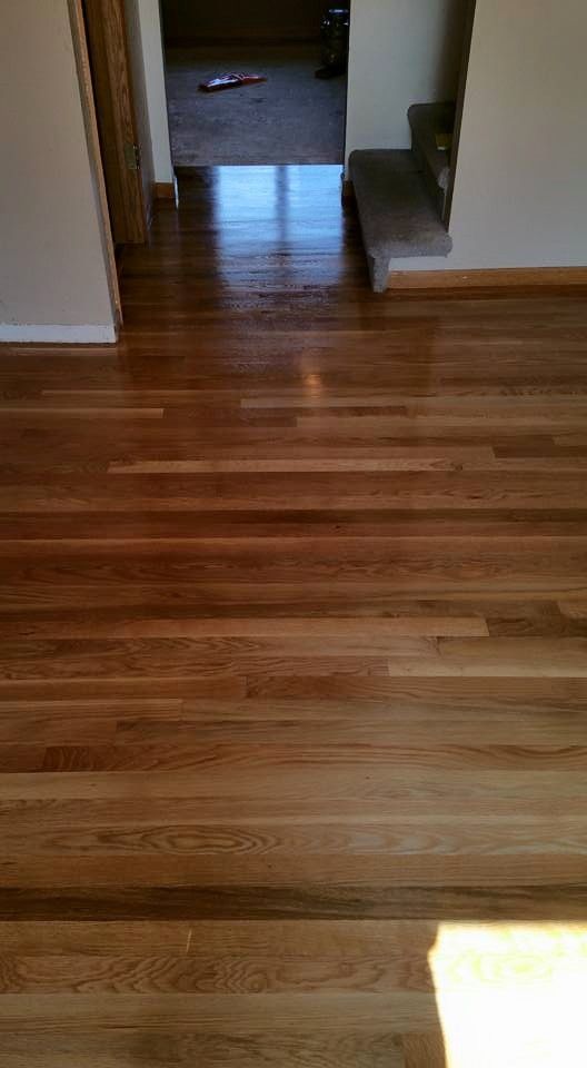 Woman in straw hat smiles, holding wine glass near a lake.