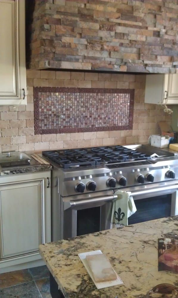 Woman in straw hat smiles, holding wine glass near a lake.