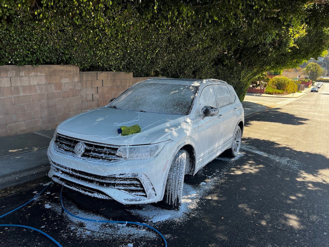 A white car is covered in foam on the side of the road.