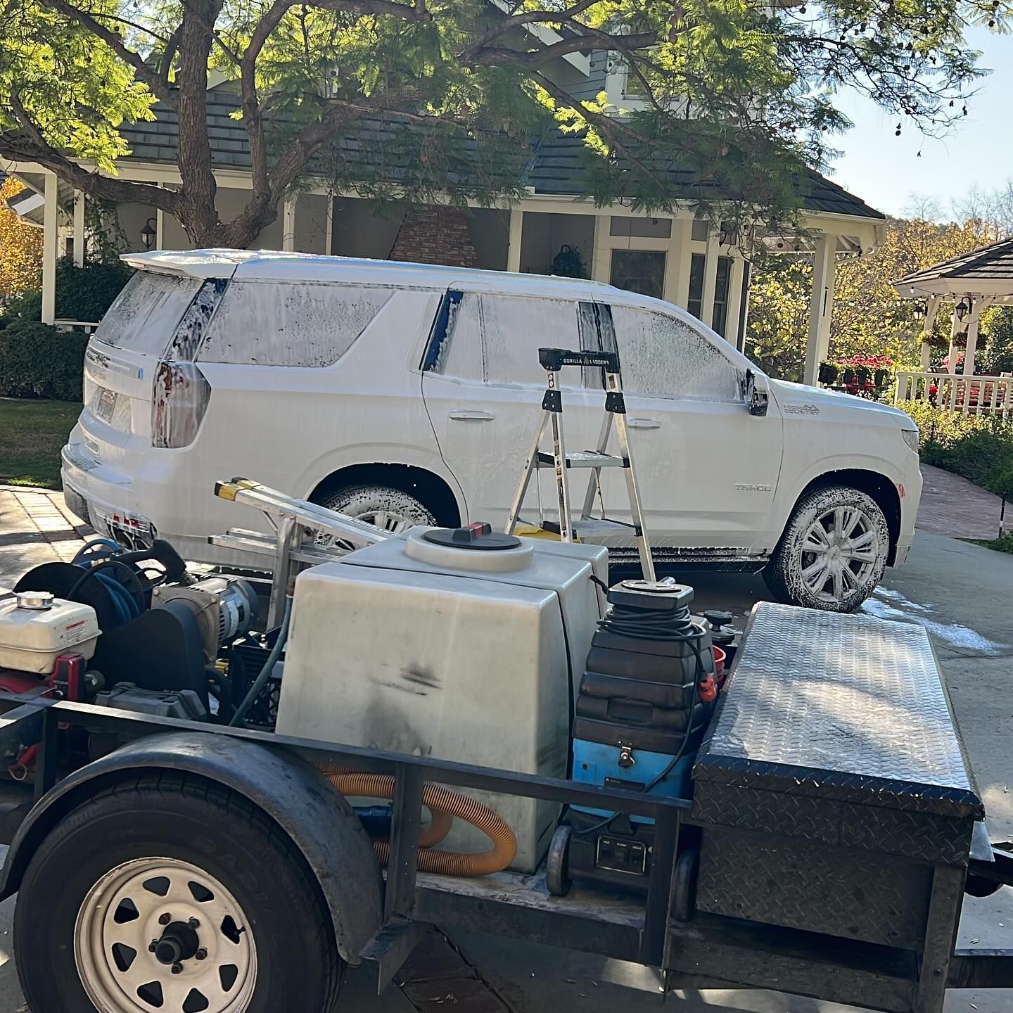 A white suv is parked in front of a house on a trailer.
