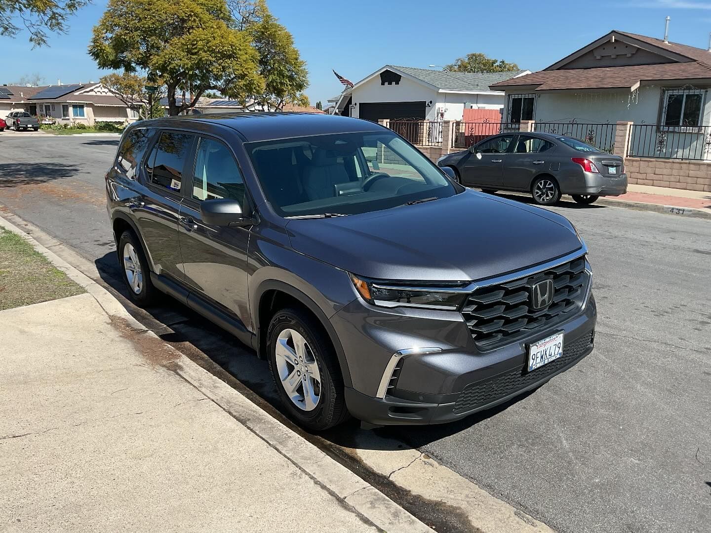 A gray honda pilot is parked on the side of the road.